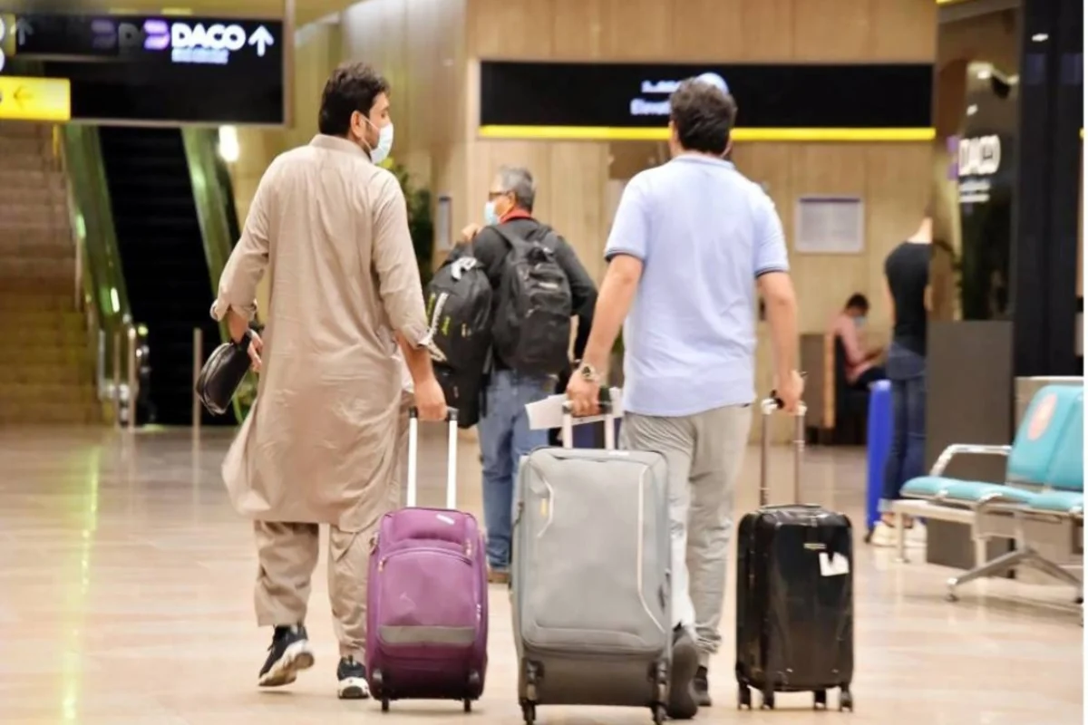 مسافران يسحبان حقائب سفرهما بمطار الملك فهد الدولي
